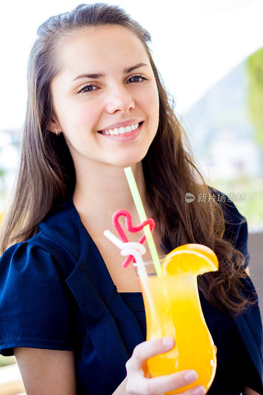 年轻女子拿着橙汁微笑着在户外