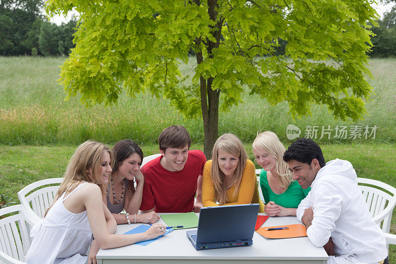 一群年轻人在户外看笔记本电脑