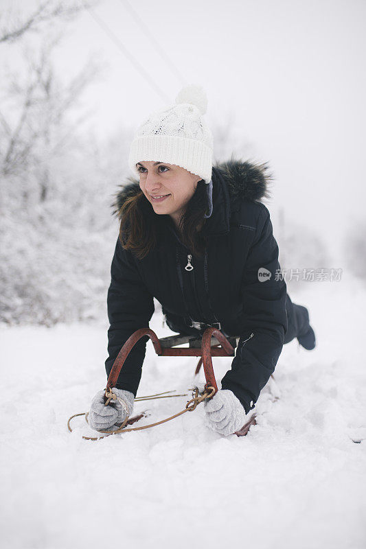 年轻女子在深雪中玩雪橇