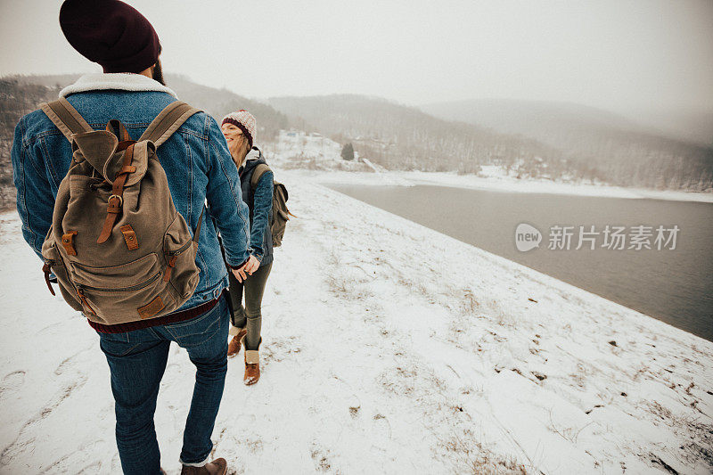 女孩拉着同伴的手漫步在雪山上