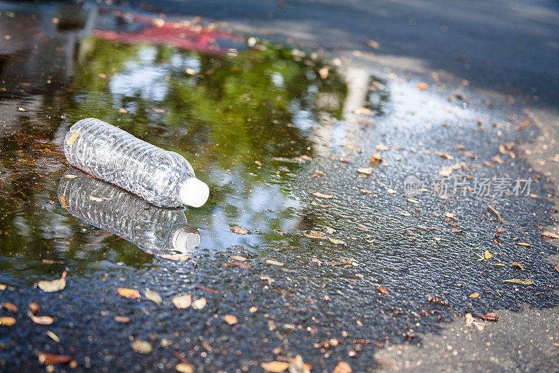 污染。丢弃在城市街道上的空塑料水瓶。
