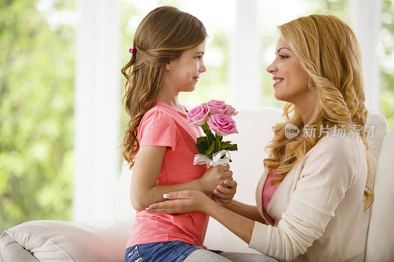 女孩面对母亲，手持鲜花
