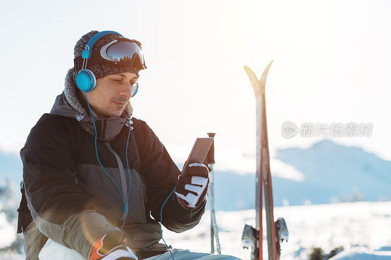 放松的滑雪者戴着耳机在山顶