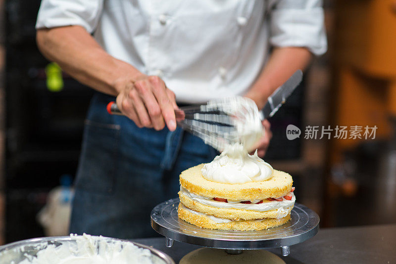 面包师在刚完成的蛋糕上涂奶油