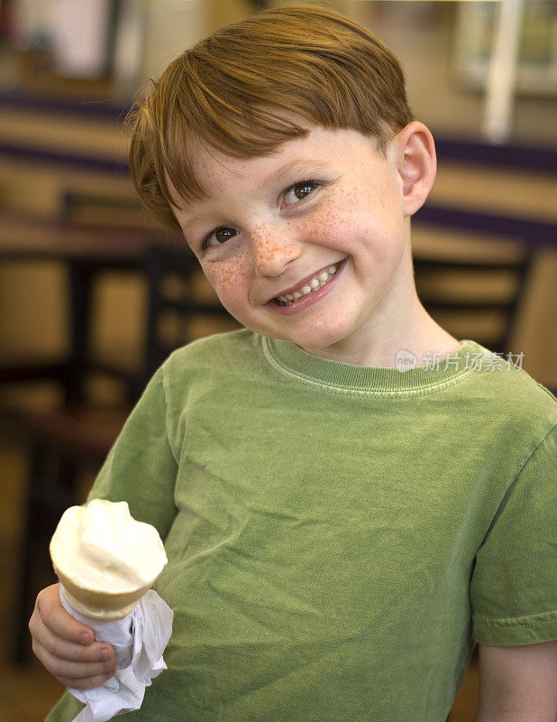 微笑的红发男孩，在冰淇淋店吃甜筒的孩子