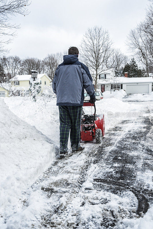 年轻人用吹雪机清理车道上的积雪