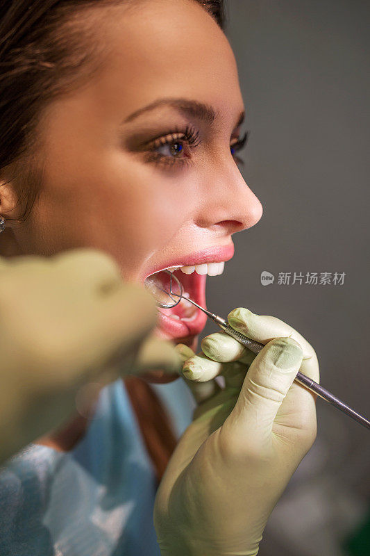 近距离的女人有她的牙齿检查牙医。