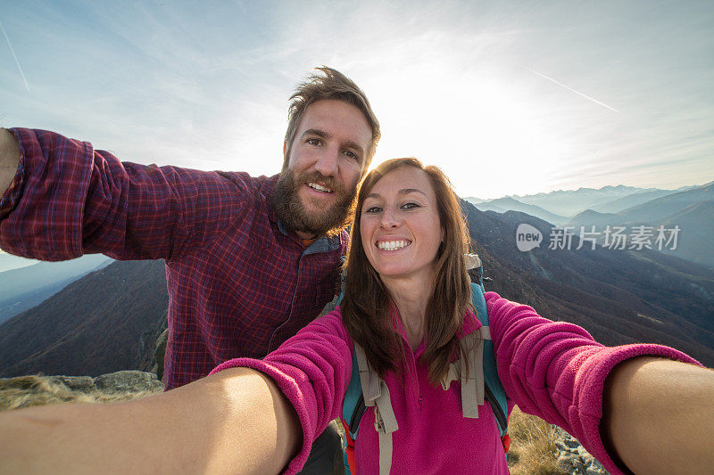 美丽的年轻夫妇徒步在山顶自拍