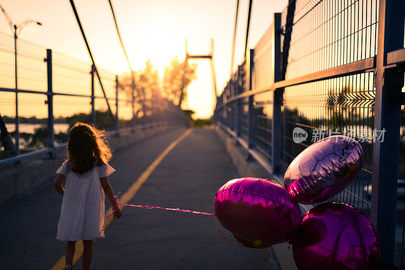 日落时分，小女孩背着气球在桥上奔跑