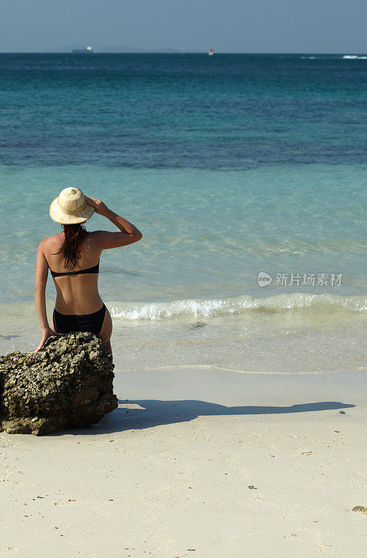 在海滩上戴着草帽的中年妇女
