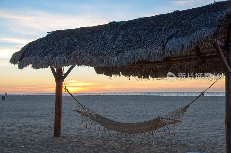 热带棕榈海滩伞和吊床在日落…特写镜头