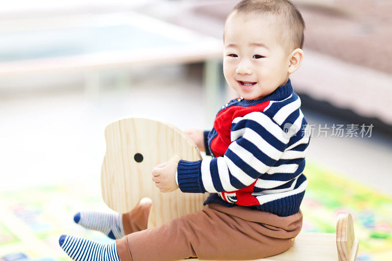 小男孩骑着木制的摇椅