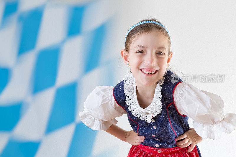 巴伐利亚小女孩穿着传统的连衣裙，叫做连衣裙和巴伐利亚旗帜