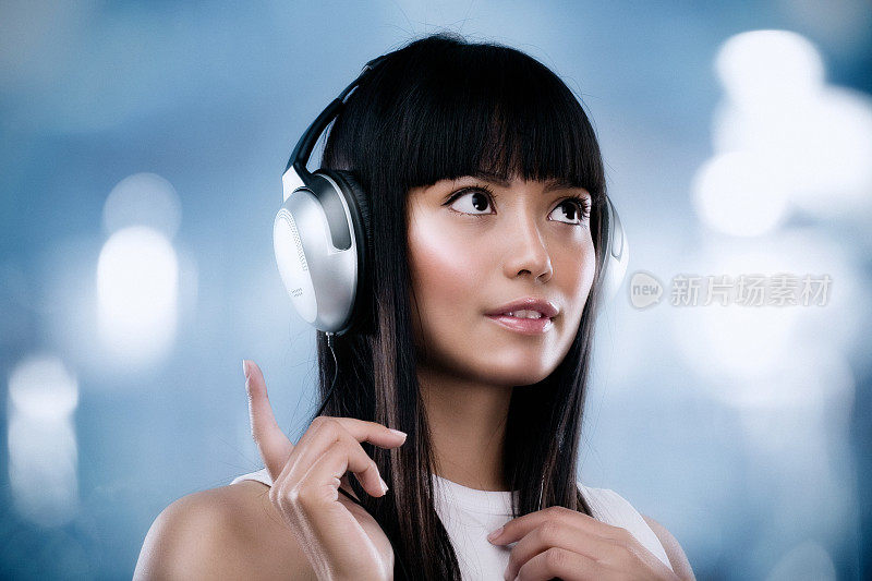 年轻的亚洲女人听耳机