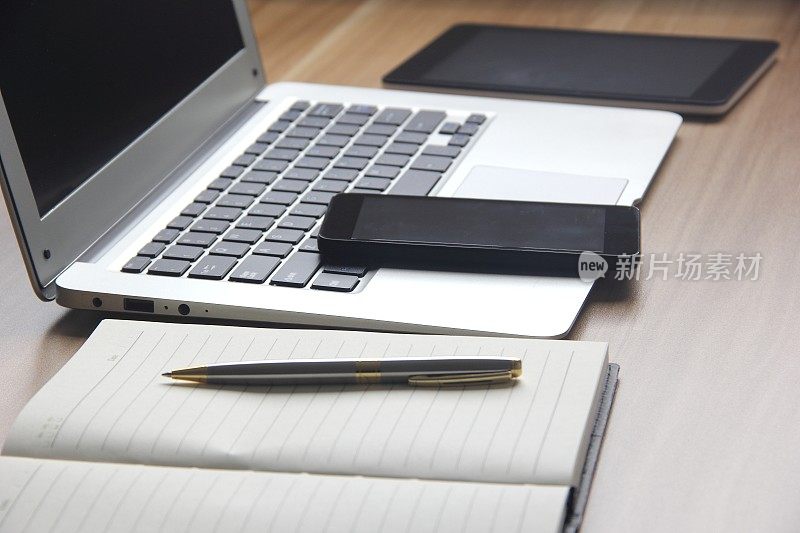 桌上有笔记本电脑、平板电脑、笔记本电脑和手机