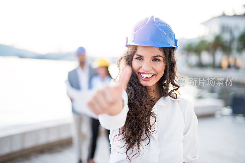 快乐的年轻女工程师在港口竖起大拇指。