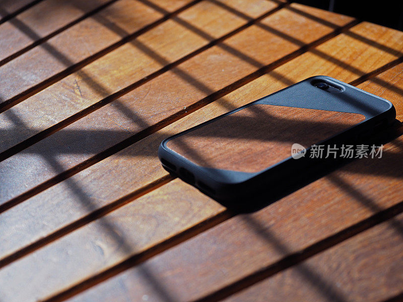 木制智能手机的后视图与真实的木质长凳纹理在背景的特写。