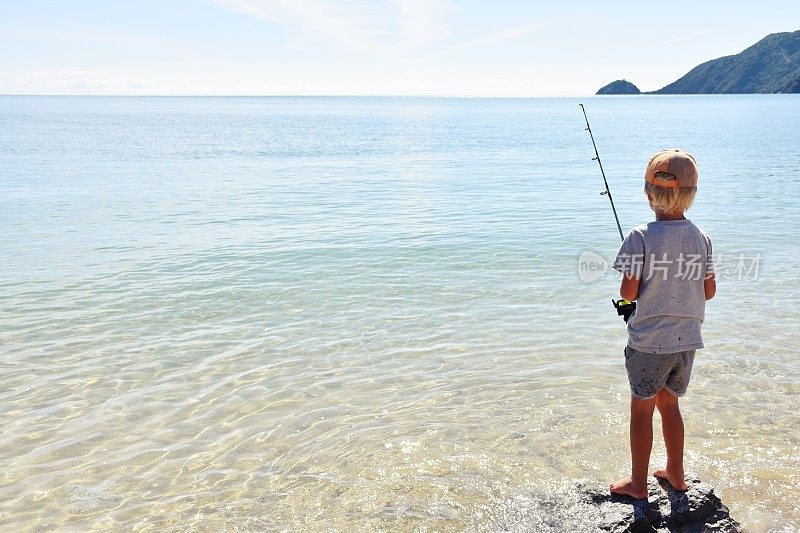 在海岸岩石上钓鱼的小孩