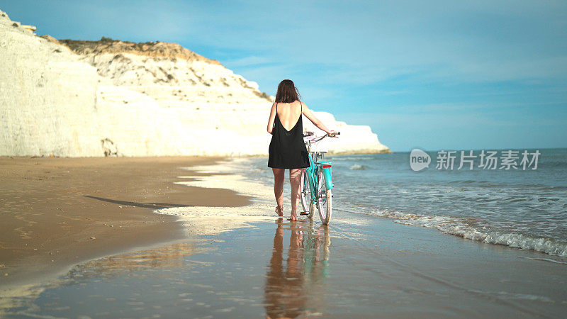 沙滩上骑着自行车的女孩