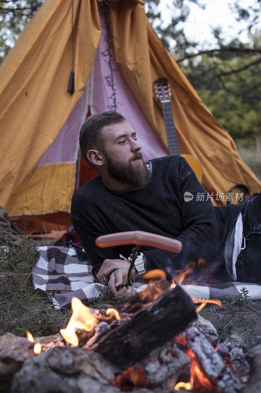 徒步旅行者在篝火上准备美味的香肠