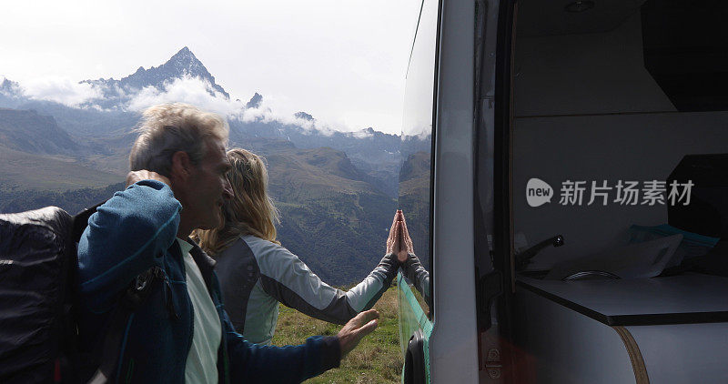 徒步旅行的夫妇在山中草地上倚靠着面包车的门放松