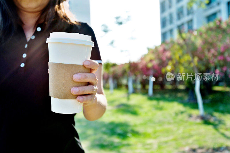 女人的手拿着一个纸咖啡杯