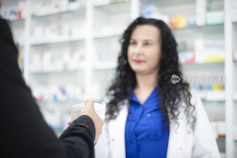 年轻女性药剂师在药店给年轻男子药物的肖像-不认识的人从女性药剂师那里得到药物