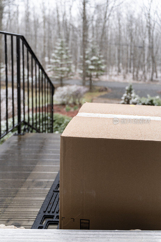 装着订好的货物的纸板箱被送到门口，下着雨放在门口的门廊上。