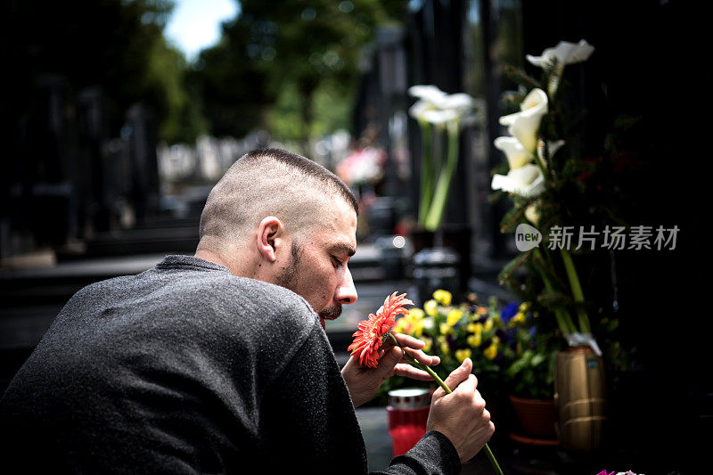 成熟的男人会因为失去最亲密的人而伤心。在墓地上拿着蜡烛的情绪紧张的男人