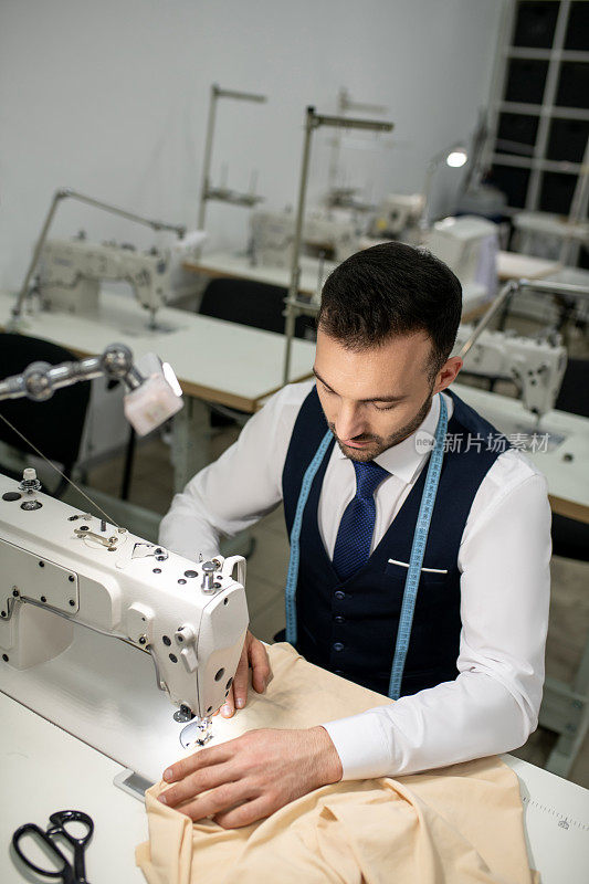 男裁缝坐在缝纫机前缝纫