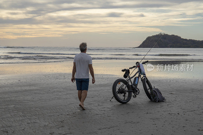 一个骑着电动自行车的人在热带海滩上散步