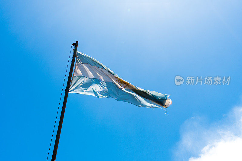 旗杆上飘扬着阿根廷国旗，背景是晴朗的蓝天