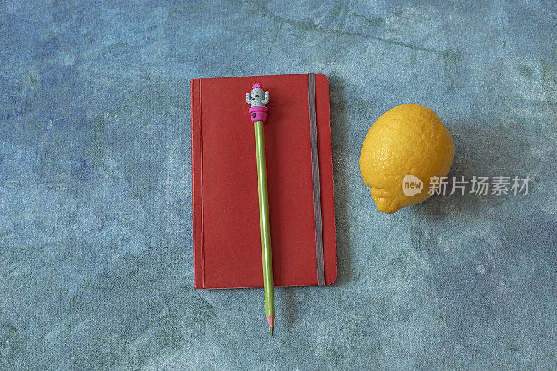 笔记本，柠檬和一支蓝色背景的笔