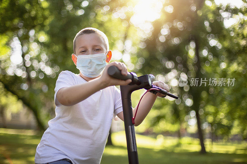 快乐的小学生微笑着戴上面具，同时使用电动滑板车