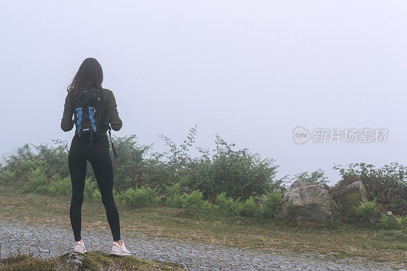 年轻女子背着背包在山里户外旅行