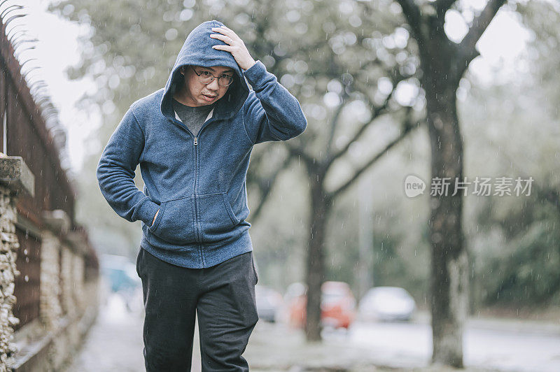 一个亚裔华人在雨中行走在街上