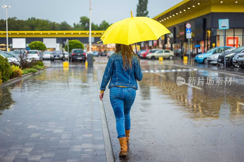 年轻女子转身走在雨中