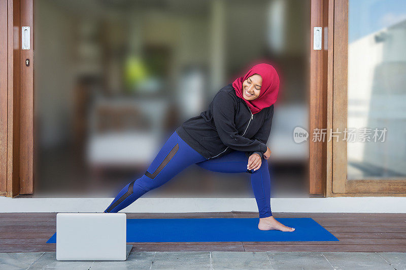 快乐的马来西亚穆斯林教练做弓步热身运动在她的教学视频