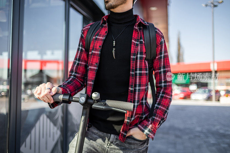 技术、生态的移动性概念。一个赶时髦的年轻人骑着电动滑板车，双手握住滑板车的把手。