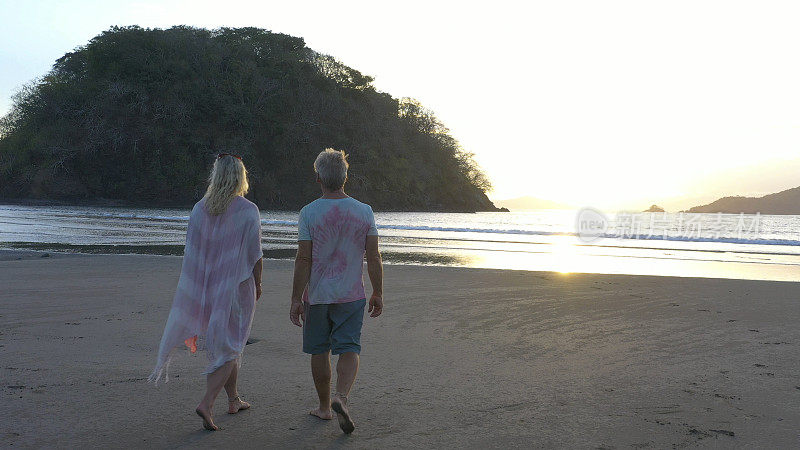 一对成熟的夫妇早上在沙滩上散步