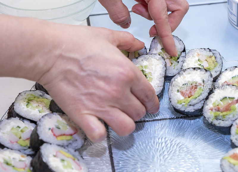 女孩的手正在准备寿司卷。日本料理在家。