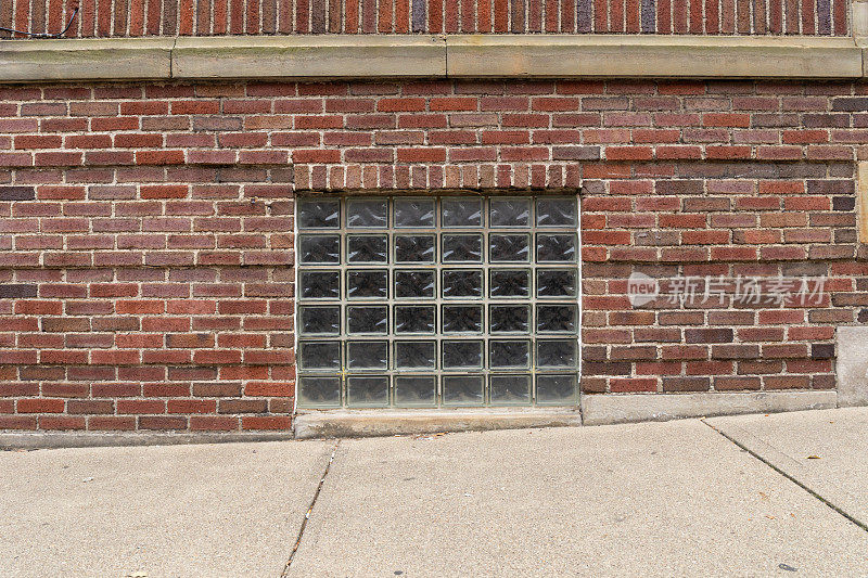 在一幢旧红砖建筑的地下室的玻璃块窗户，倾斜的人行道前景
