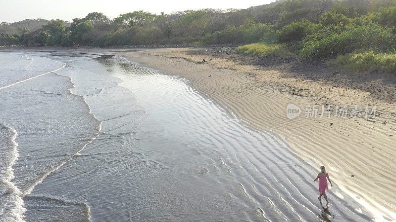 鸟瞰图的女人走下沙滩在日出