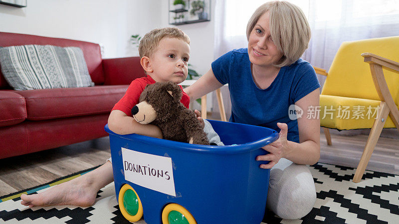 小男孩坐在一个盒子里，抱着一只泰迪熊