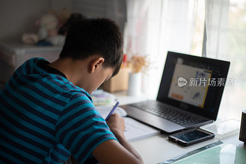 亚洲年轻男学生在家通过笔记本电脑在线学习。