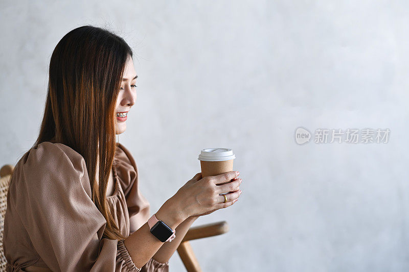 年轻女子微笑着拿着一杯咖啡。