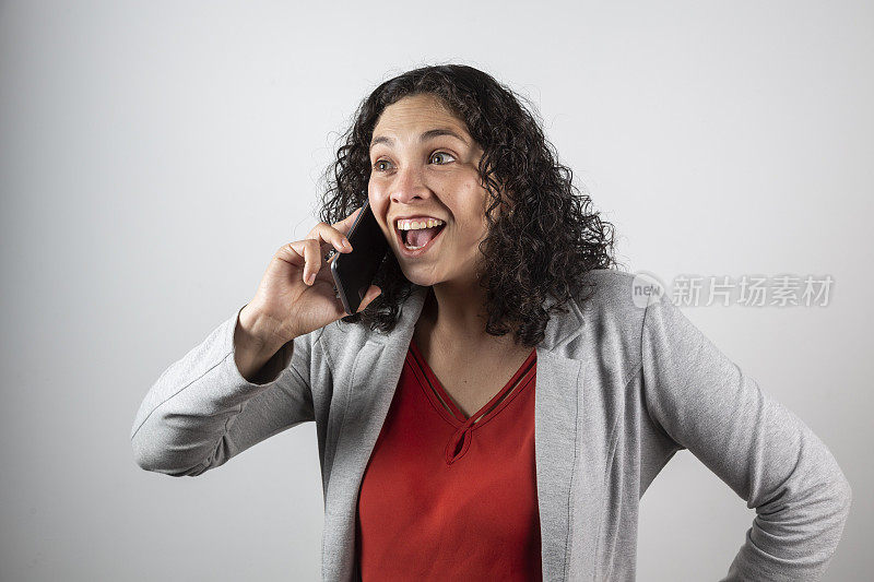 一个三十多岁的拉丁女人拿着手机在摄影棚拍照