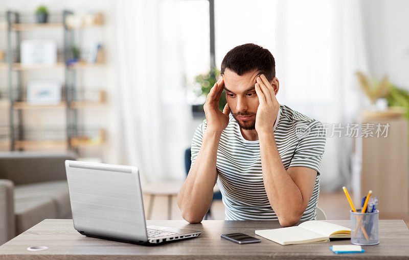 有压力的男人用笔记本电脑在家庭办公室工作