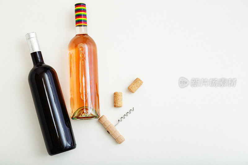 玫瑰酒瓶和红酒酒瓶的开塞钻和软木塞。简约的葡萄酒构成俯视图在白色背景。两瓶Wine品牌的模型。平铺与复制空间。
