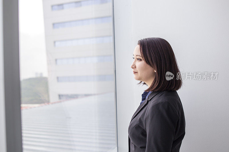 一个日本女人从办公室的窗户往外看